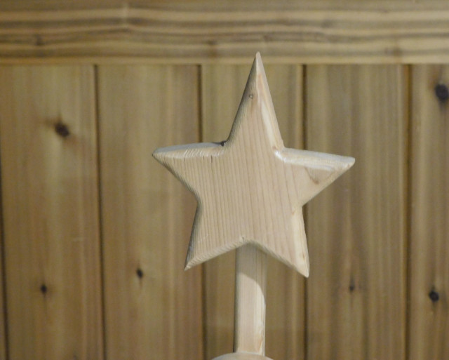 Background is wooden board panelling. In the centre is a five-pointed wooden star, made of different wood than the pine panelling. 